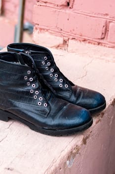 Old black discarded boots in a landfill close up