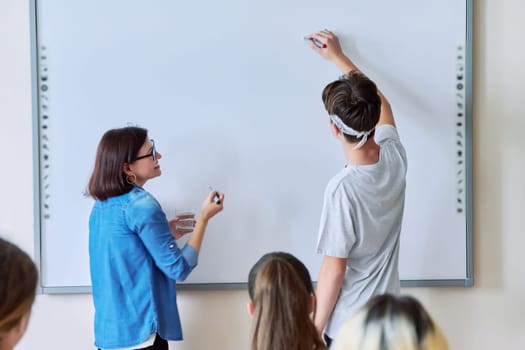 Lesson in classroom with digital screen for group of teenagers. Teaching, discussion with teenage students. Technology, education, knowledge, high school, college, youth concept