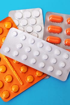Pile of packs of pills on blue background close up
