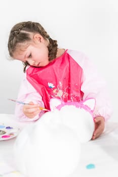 Little girl painting Halloween pumpkin with acrylic paint.