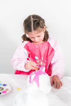 Little girl painting Halloween pumpkin with acrylic paint.