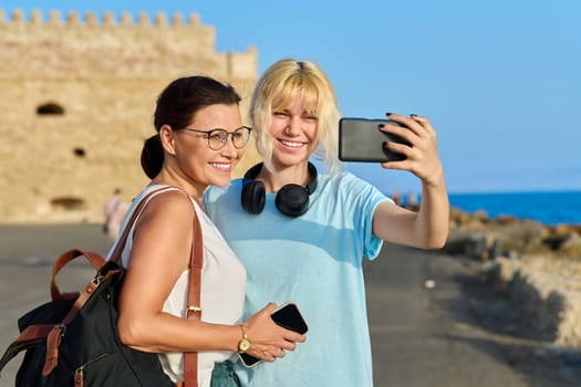 European summer vacation, mom and teenage daughter taking a selfie near the old historic fortress. Family, lifestyle, relationship, travel, tourism concept