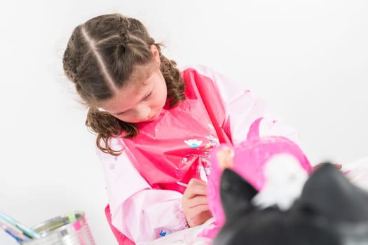 Little girl painting Halloween pumpkin with acrylic paint.