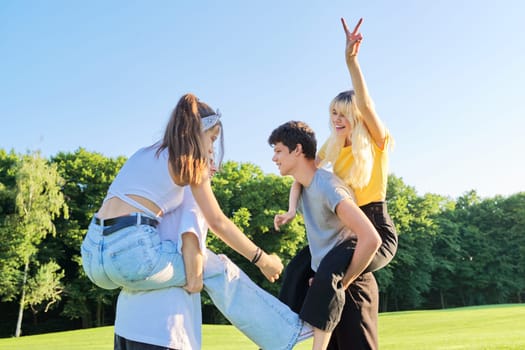 Teenage youth having fun in the park, happy laughing friends. Group of teenagers together on sunny day. Friendship, adolescence, summer, vacation, lifestyle, fun, happiness, holiday, leisure, people