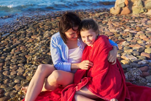 Happy mother and daughter child together on the sea beach, embracing, enjoy nature, communication, family vacation