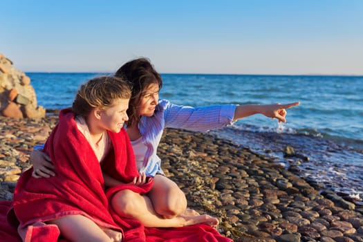 Happy mother and daughter child together on the sea beach, embracing, enjoy nature, communication, family vacation