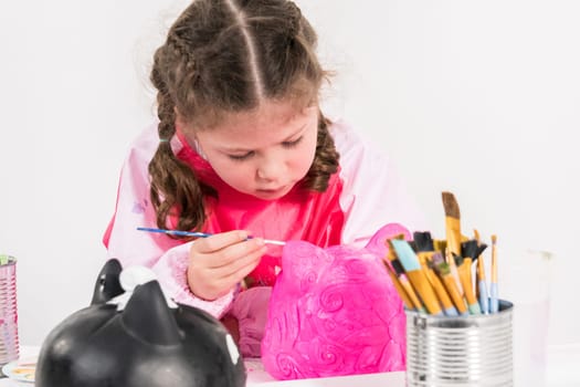 Little girl painting Halloween pumpkin with acrylic paint.