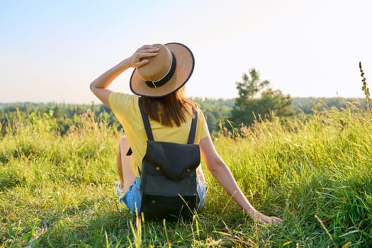 Back view, woman with backpack in hat enjoying summer landscape of wild nature. Summertime, nature, recreation, active healthy lifestyle, travel, tourism, hike, people concept