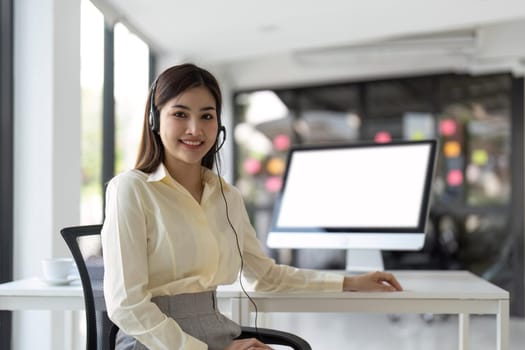 Portrait of happy smiling female customer support phone operator at workplace. Smiling beautiful Asian woman working in call center.