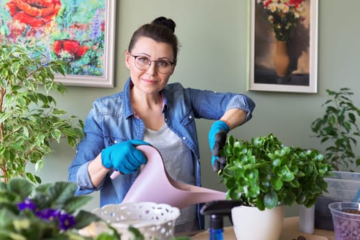 Woman with home plants in pots. Hobbies and leisure, green pets in pots, home jungle, happy female blogging about houseplants, watering plant with water from watering can