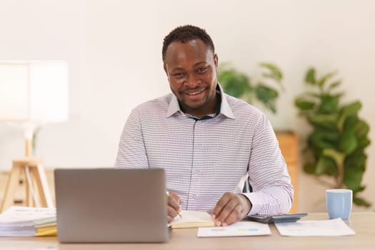 Smiling American African makes financial report and studies annual figures, analyzes profits. Accountant checks status of financial.