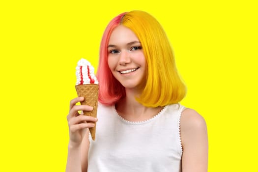 Smiling happy beautiful model teenager with ice cream in waffle cone over yellow studio background. Summer, food, beauty and fashion concept