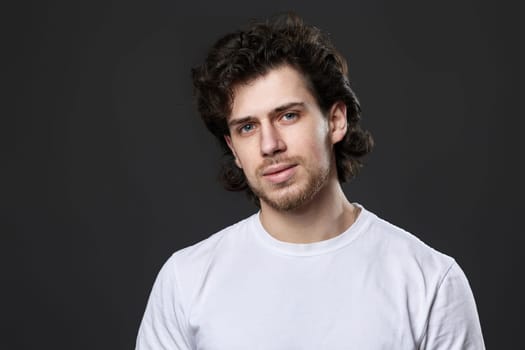 portrait of calm young bearded man on dark gray background