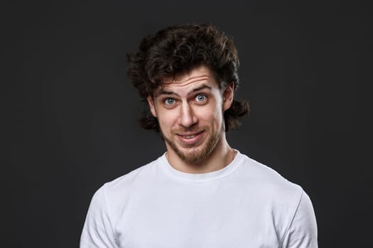 embarrassed bearded man in casual white t-shirt looking at the camera on dark gray background. great idea