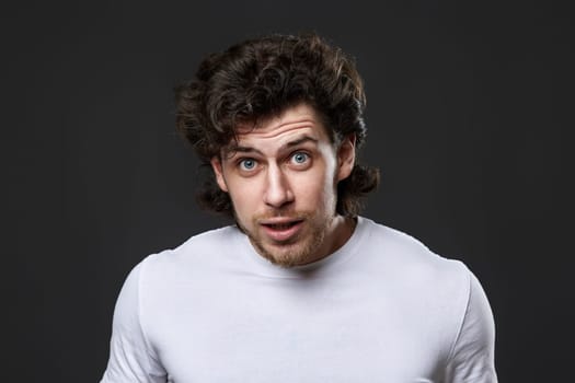 portrait of surprised young bearded man on gray backround
