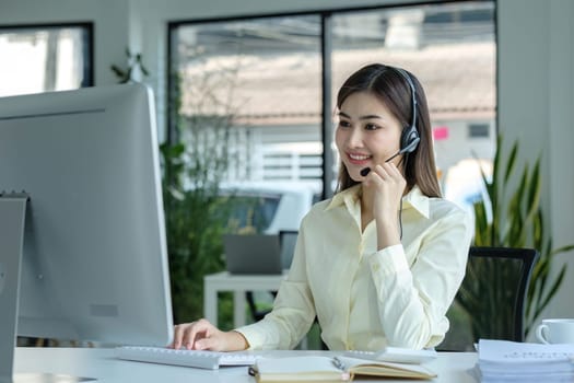 close up call center operator in wireless headset talking with customer, woman in headphones with microphone consulting client on phone in customer support service, looking at computer screen