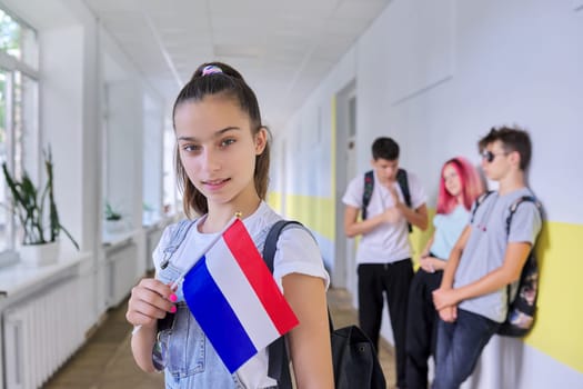 Student teenager girl with Netherlands flag inside school, school children group background. Europe, Netherlands, education and youth, patriotism people concept