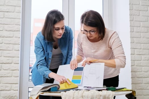 Interior design, working women designers choosing samples of fabrics and accessories for curtains