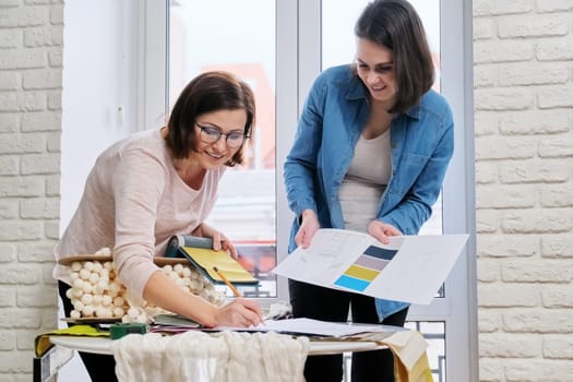 Interior design, two working colleagues designers, or decorator and client choosing curtain fabrics, women looking at samples discussing curtain models