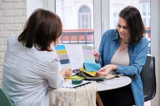Interior design, working women designers choosing samples of fabrics and accessories for curtains
