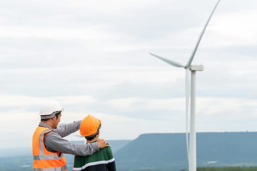 Engineer with his son on a wind farm atop a hill or mountain in the rural. Progressive ideal for the future production of renewable, sustainable energy. Energy generation from wind turbine.