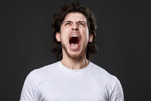 annoyed angry curly bearded man feel outraged on dark gray studio background