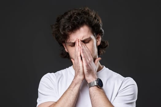 Portrait of frustrated young man on dark gray background. sadness