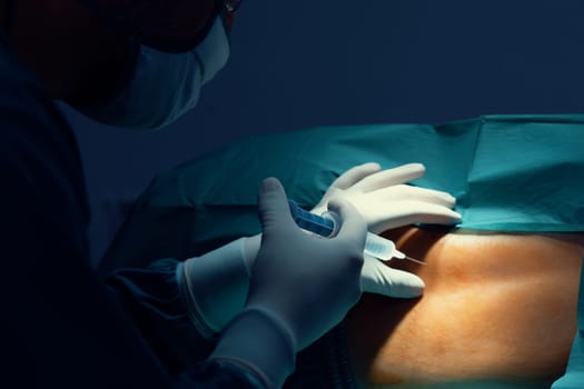 Surgeon inject anesthesia with syringe into the patient before perform surgery in sterile operation room with modern surgical equipments. Medical surgery perform by professional and confident surgeon.
