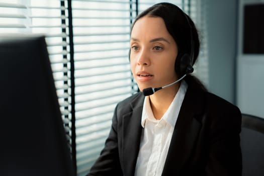 Competent female operator working on computer and talking with clients. Concept relevant to both call centers and customer service offices.