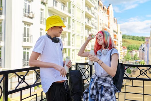 Urban lifestyle of teenagers, couple of college students talking having rest drinking milk drink in bottle outdoors, city street background. Healthy food, youth, recreation and communication concept