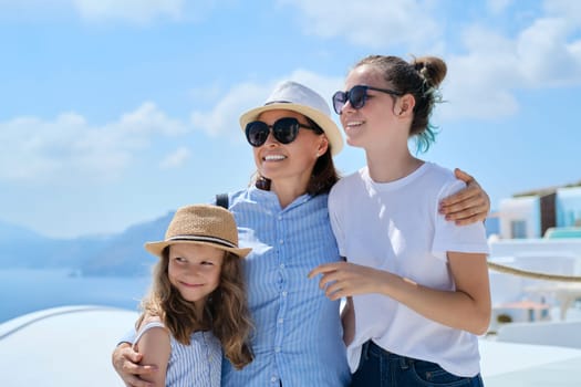 Tourism, travel, Greece, Santorini. Happy travelers mom and daughters laughing and talking on famous tourist island