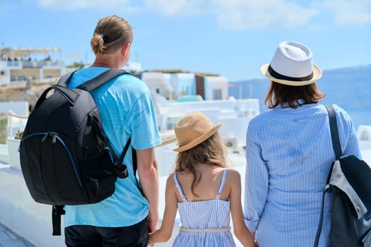 Tourism, travel, family, vacation concept. Mom dad and daughter happy travelers on the famous picturesque Greek island of Santorini, Mediterranean sea cruise