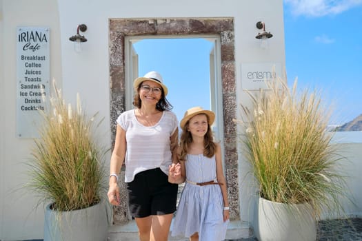 11.09.2019. Santorini island in Greece, Fira. Photo zone, open door to balcony with picturesque seascape, mother and daughter tourists posing for photo