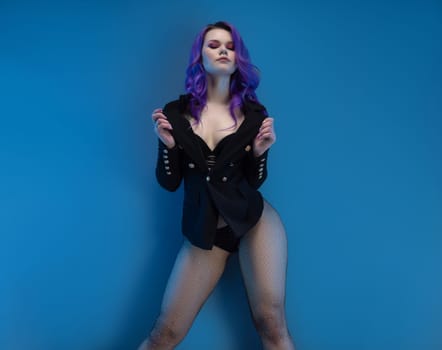 sexy girl in a fancy jacket and purple hair posing erotically in her underwear against a blue background copy paste
