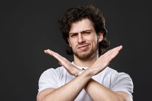 young bearded man showing stop gesture on dark gray background