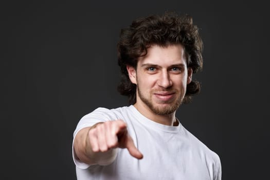 amazed caucasian man pointing finger at you on dark gray background
