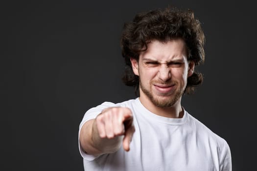 amazed caucasian man pointing finger at you on dark gray background