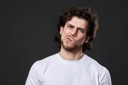 skeptic and nervous man in white t-shirt looking suspicious on dark gray background