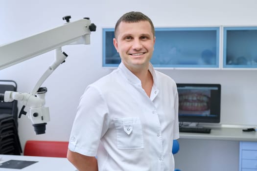 Portrait of happy friendly male dentist, smiling professional doctor looking at camera in dental clinic