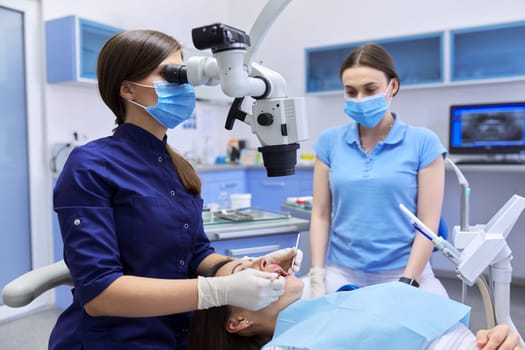 Healthcare dentistry medicine, woman doctor dentist treats teeth using dental microscope and tools. Professional modern dental equipment
