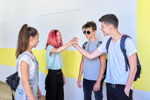 Meeting of teenage students at school, greeting and hugging. Friendship, school, college, teenagers concept