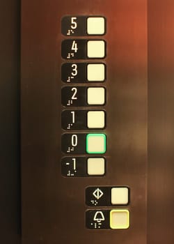 Elevator buttons, number 0 in green, blind, text in Braille alphabet under numbers, for blind disabled people.