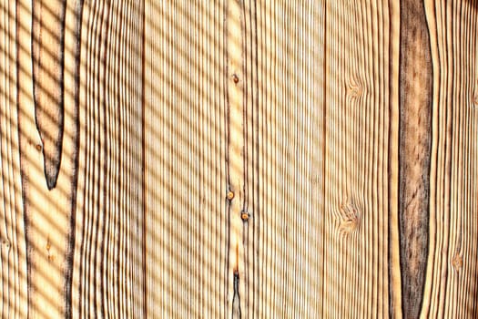 Desk made from wooden boards lit by morning sun, shades leaving diagonal stripes pattern