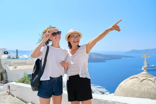 Two happy smiling women, mother and teenage daughter traveling together, luxury travel to the famous greek island of Santorini