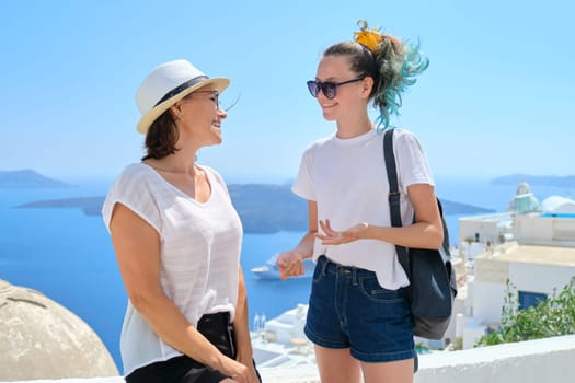 Two happy smiling women, mother and teenage daughter traveling together, luxury travel to the famous greek island of Santorini