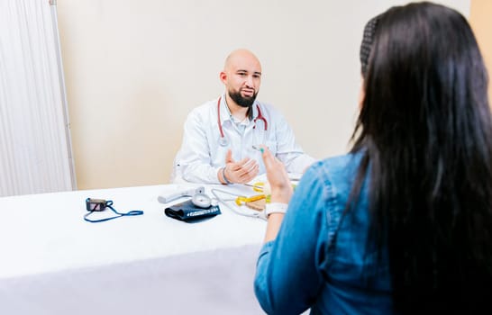 Back view of a female patient talking to the nutritionist. Smiling nutritionist explaining to a female patient, Nutritionist man talking to woman patient in office