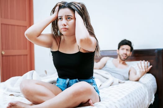 Young couple arguing sitting on the bed. Concept of couple problems in bed. Upset woman with husband sitting on bed, Wife arguing with her husband in bed