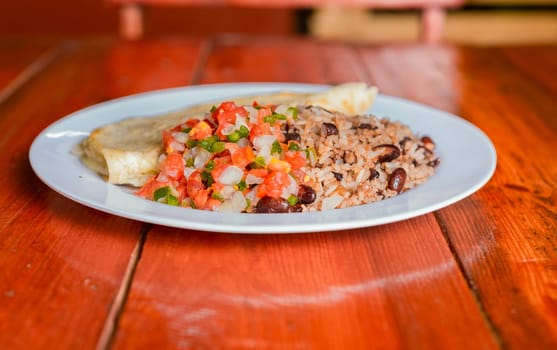 Traditional Gallo Pinto Meal with Pico de Gallo and quesillo served, Gallopinto dish with quesillo and pico de gallo on wooden table