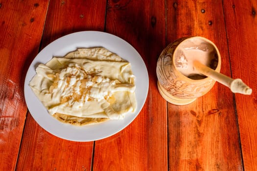 Delicious traditional Quesillo with cocoa drink. Quesillo plate with cocoa drink served on wooden table. Typical Nicaraguan food and drinks.