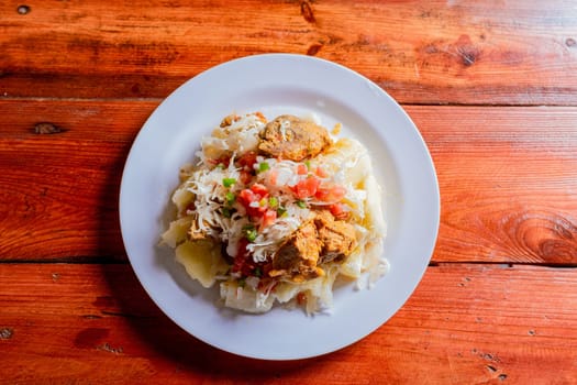 Top view of traditional Chancho dish with Yuca. Nicaraguan pork with yucca served on wooden table